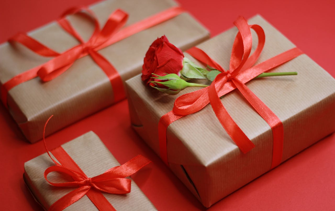 gallery-5 Elegant gift boxes tied with red ribbons and a rose on a red background.