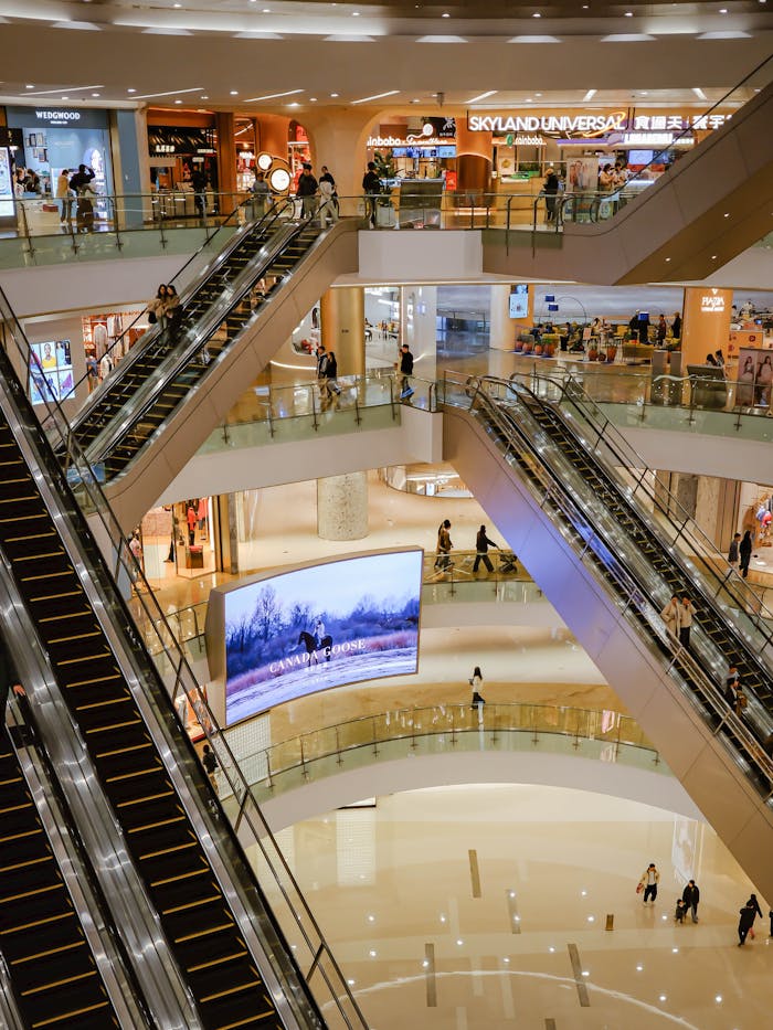 services-02 Busy multi-level shopping mall featuring escalators and shoppers.