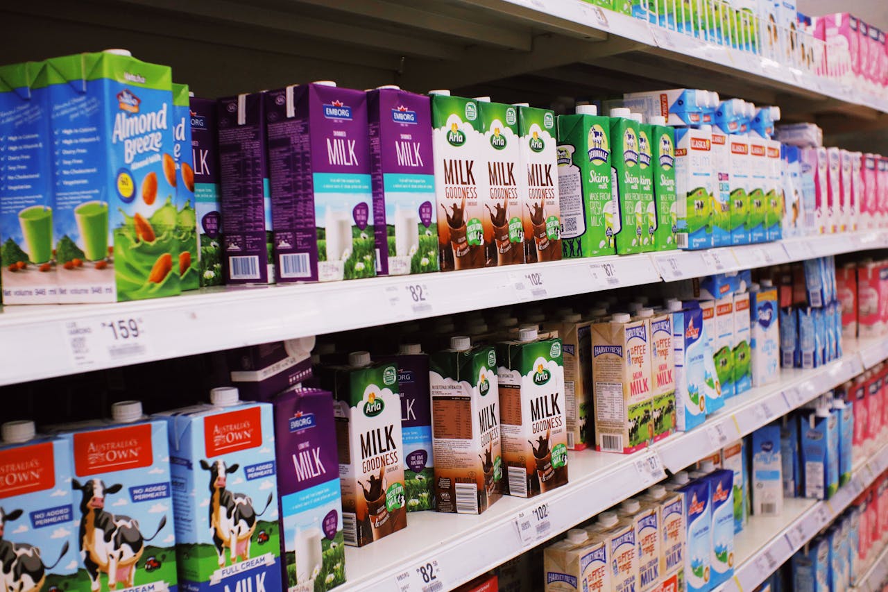 hero-img-02 Various colorful boxes of milk placed on shelves with prices in modern supermarket